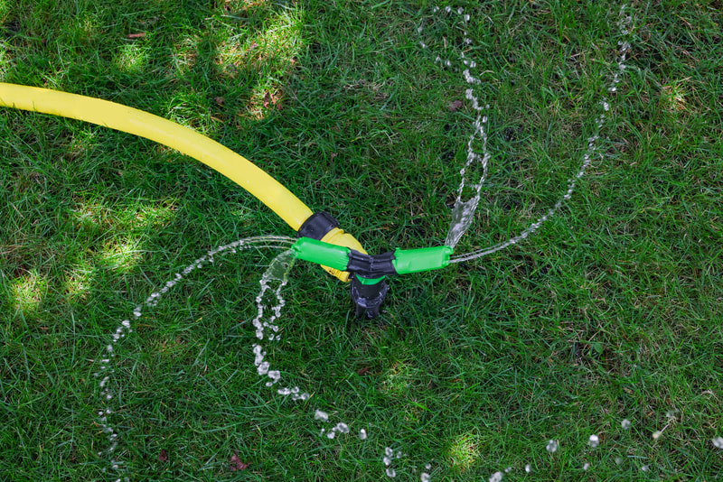 a hose connected to a sprinkler in the grass